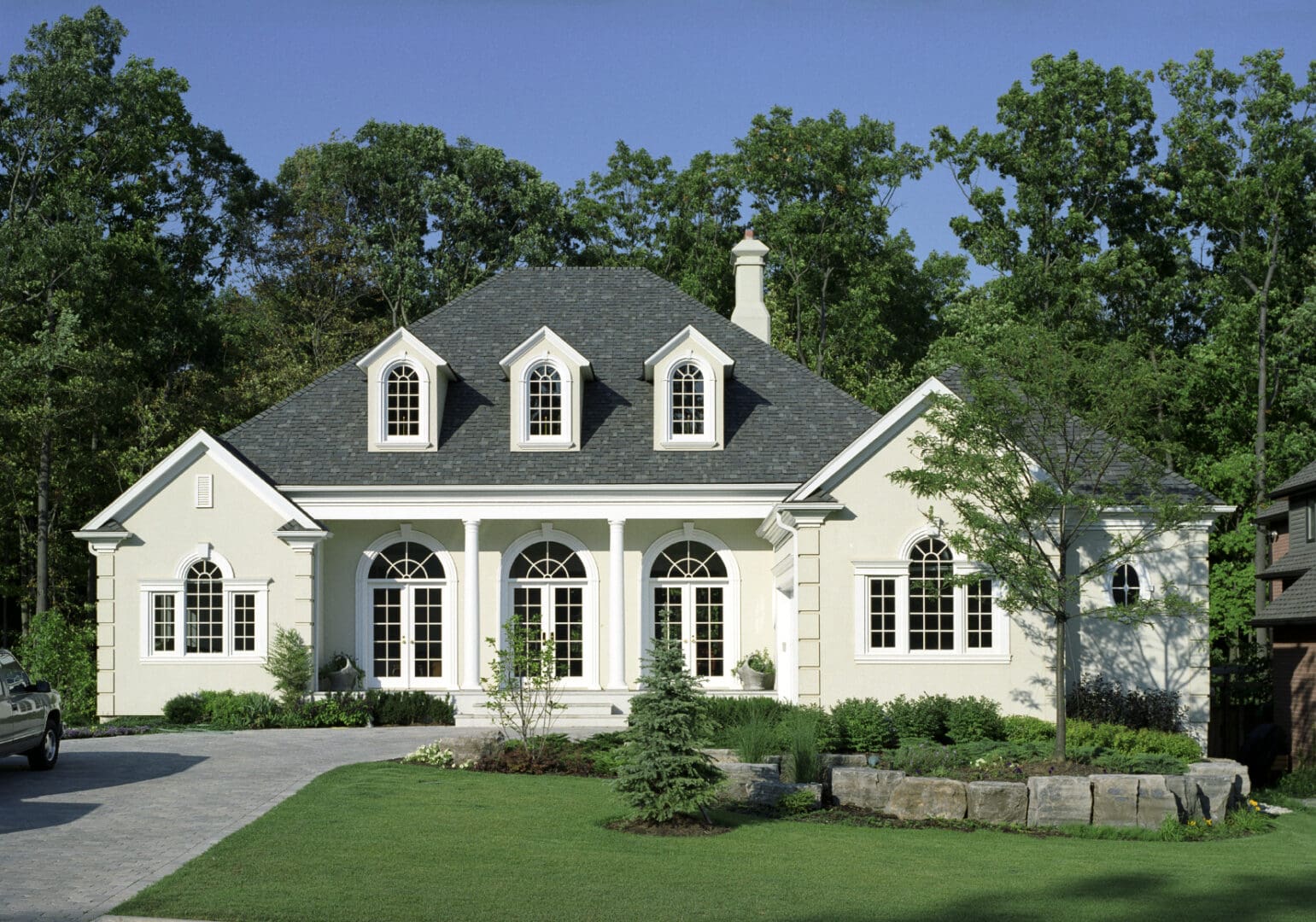 A white house with a green roof and trees in the background.