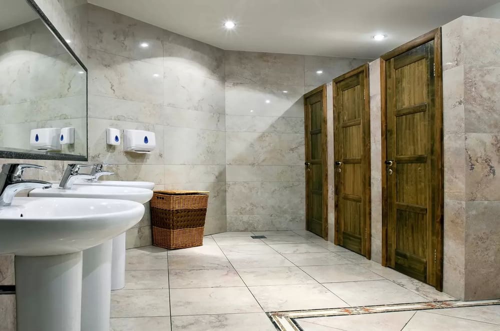 A bathroom with two sinks and three wooden doors.