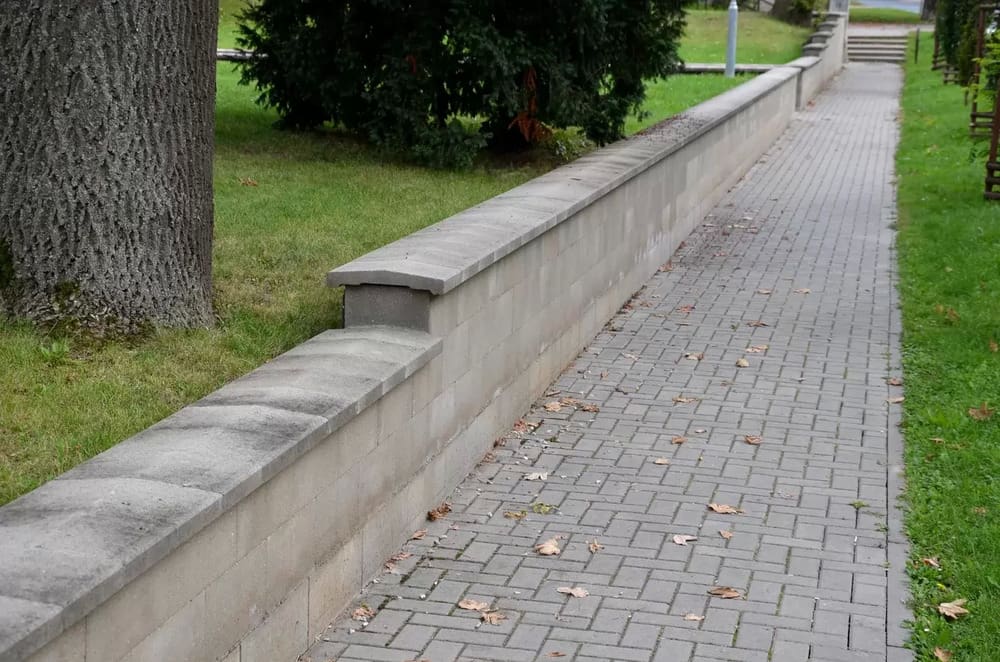 A brick wall with a bench on the side of it.