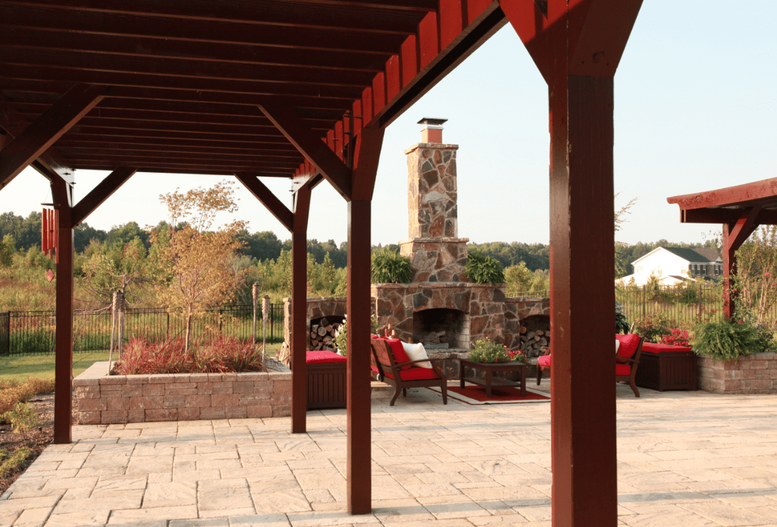 A patio with a fire place and red chairs.