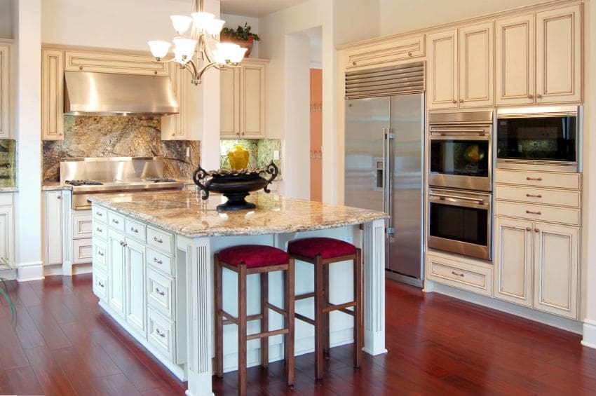 A kitchen with white cabinets and red stools.